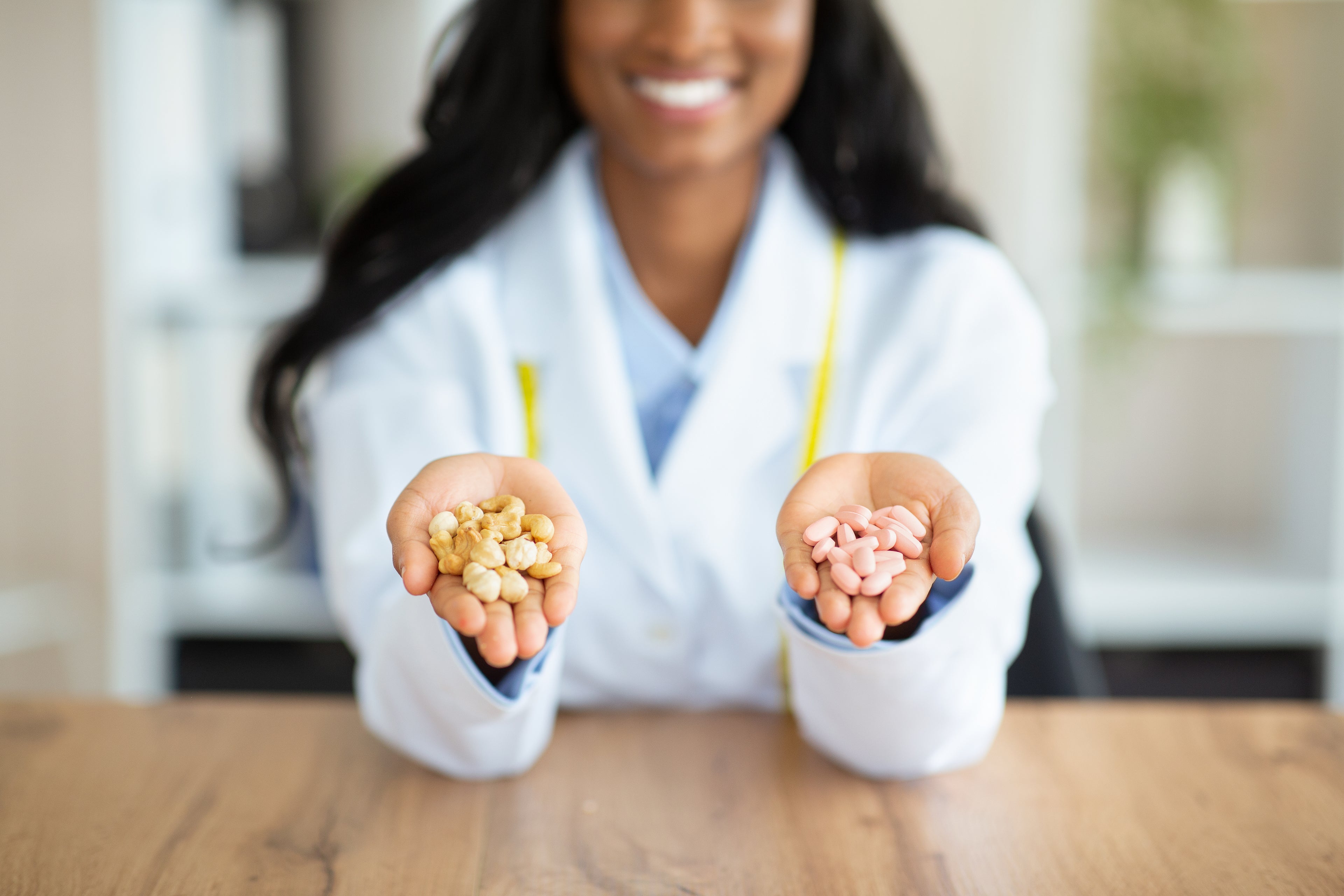 Smiling woman in a lab coat holding two handfuls of supplements, representing women's health and nutritional support